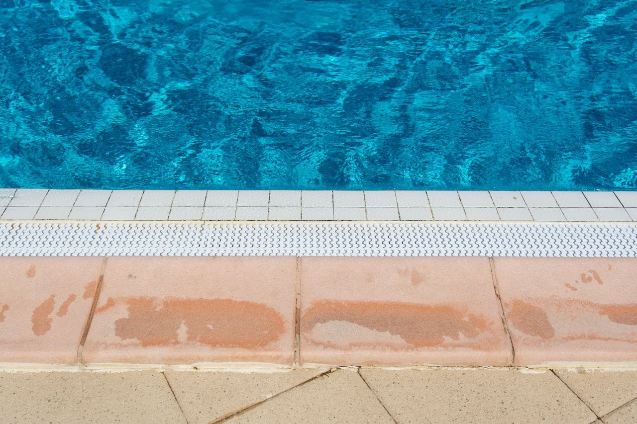 Close-up of pool edge with tile coping and blue water
