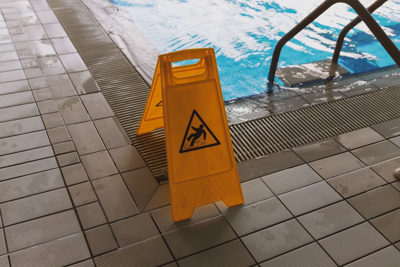 Yellow wet floor caution sign beside indoor pool