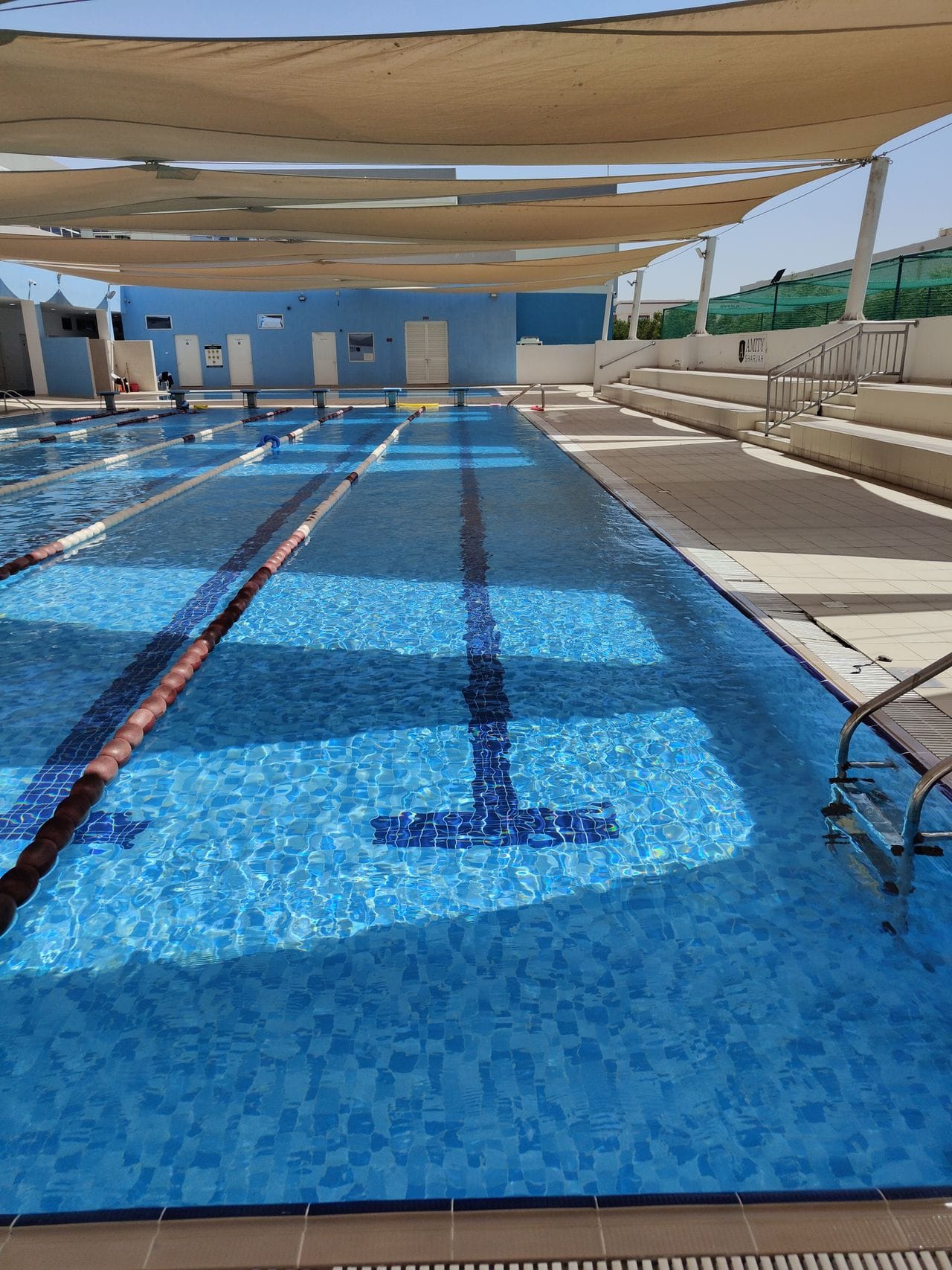 Outdoor lap pool with lane dividers under shade sails