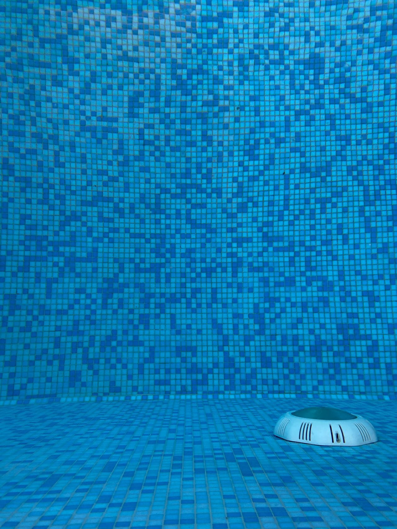 Underwater view of blue mosaic pool tiles with light fixture