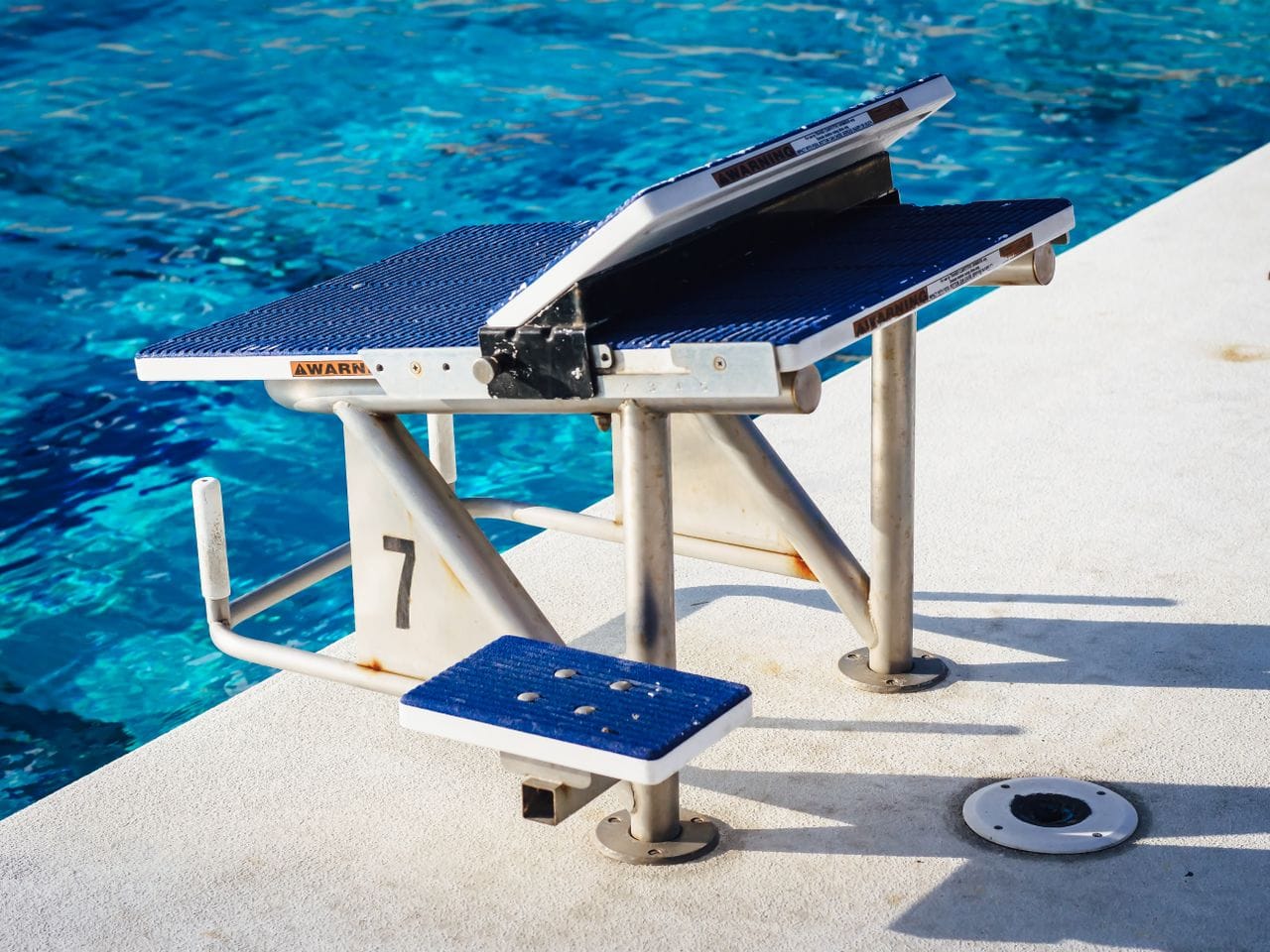 Racing starting block numbered seven at edge of swimming pool