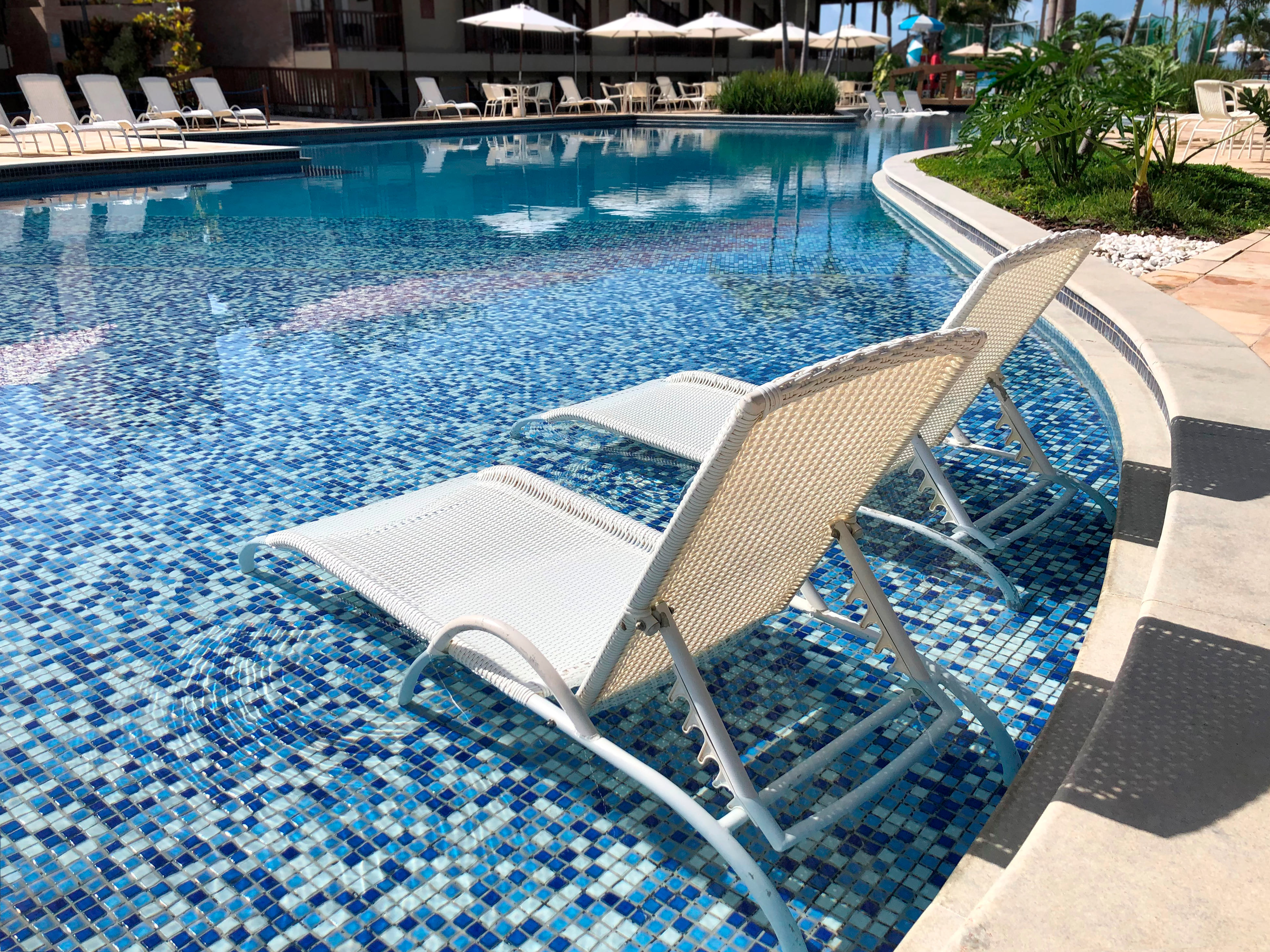 Swimming pool with crystal-clear blue water and surrounding sun loungers