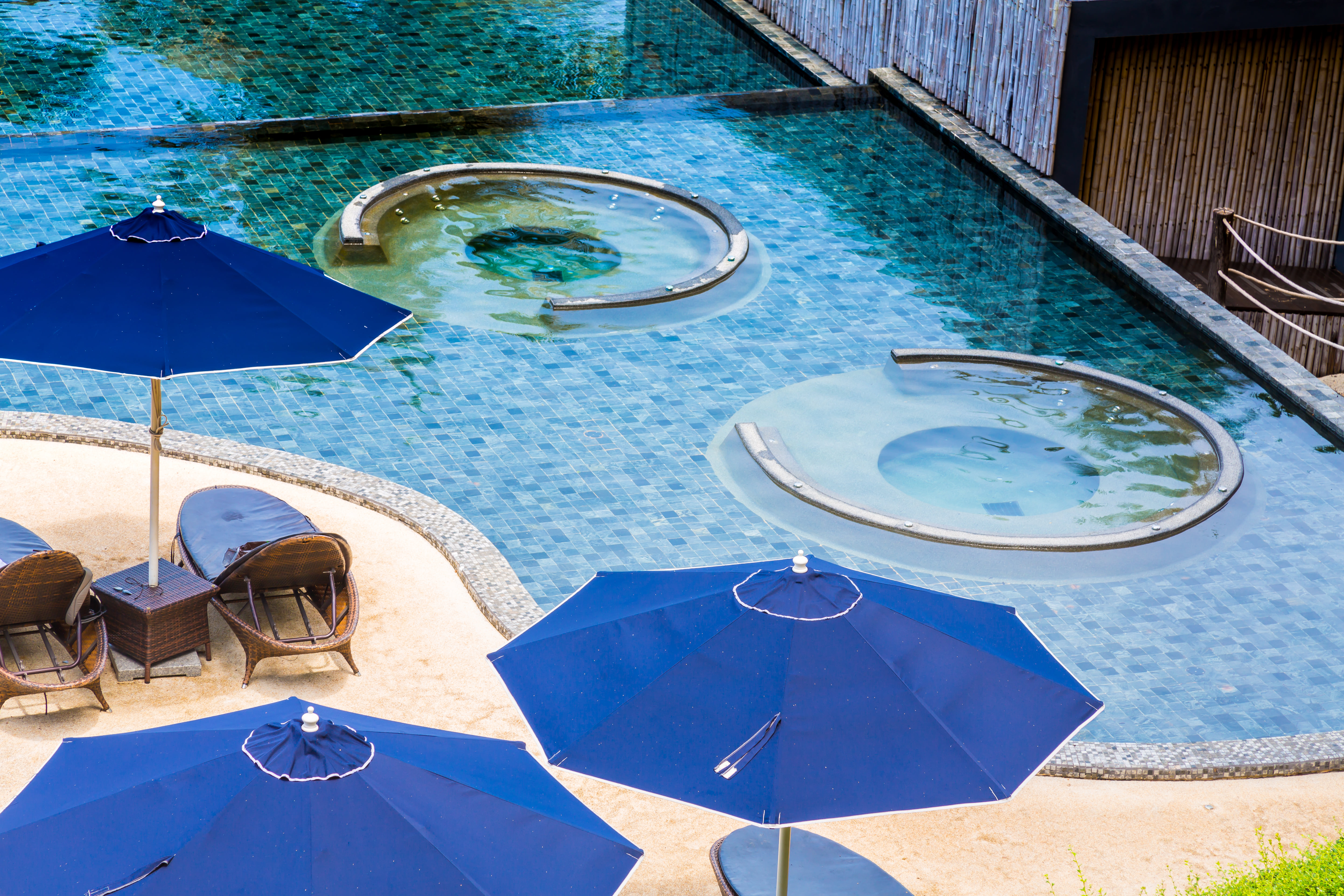 Luxury resort swimming pool with blue sun umbrella and clear blue water