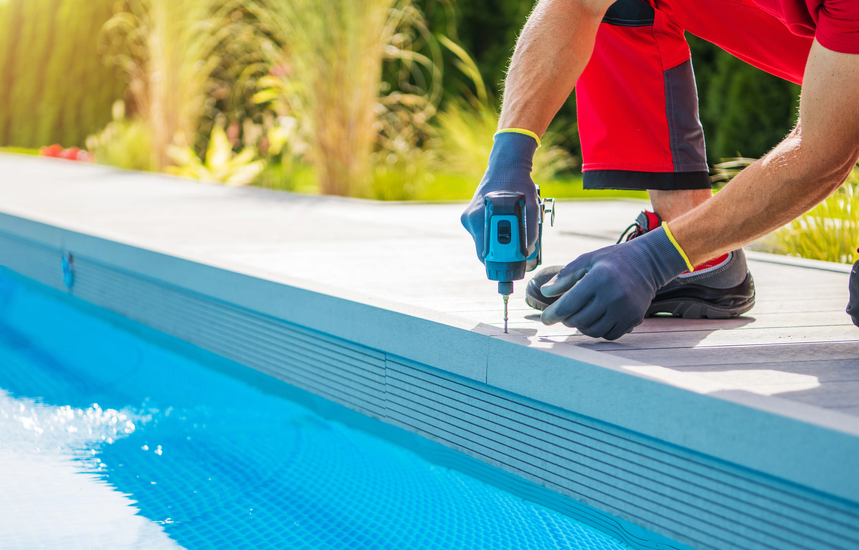 Pool technician repairing the pool edge with a power drill