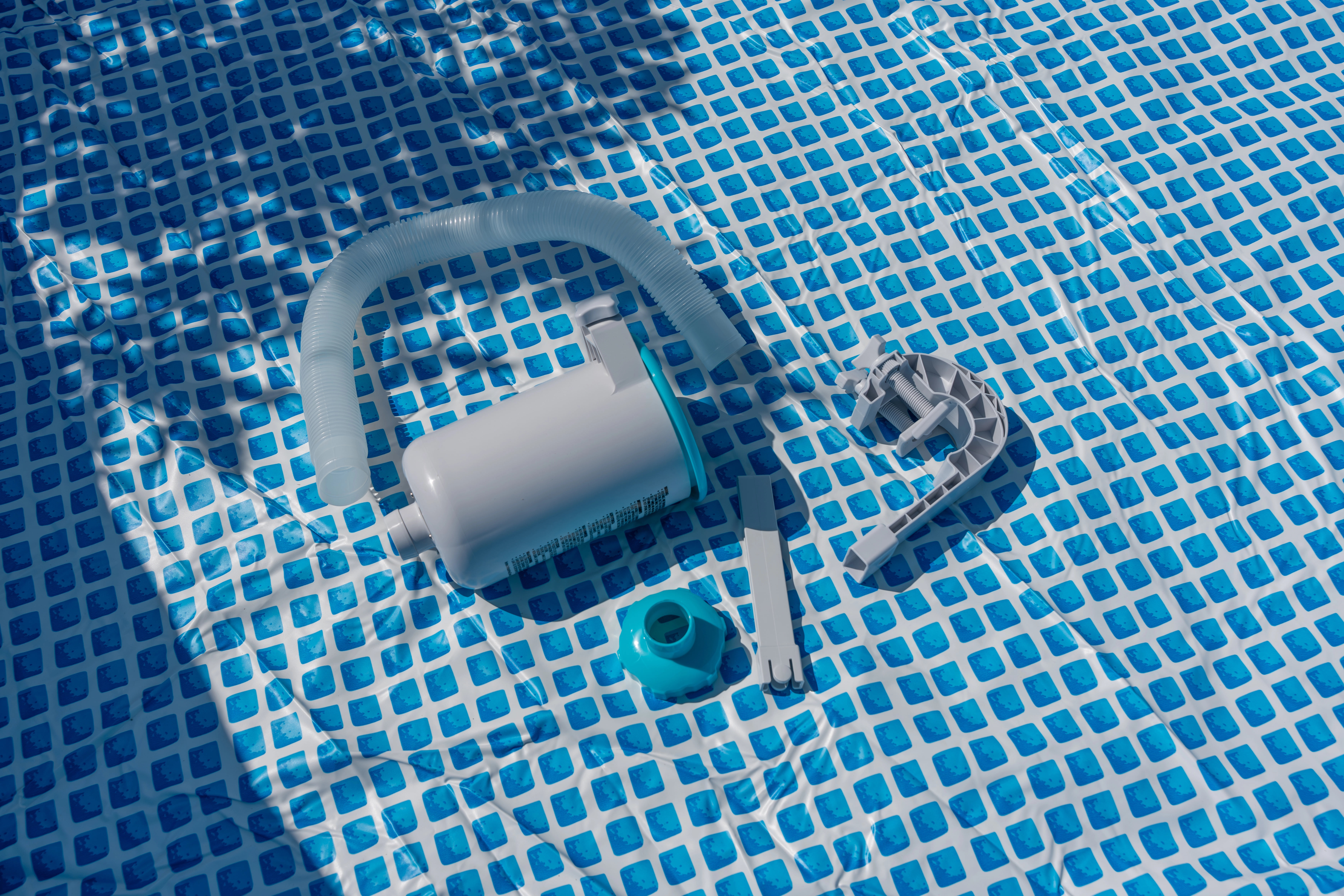 Pool cleaning equipment and vacuum components resting on the tiled bottom of a swimming pool