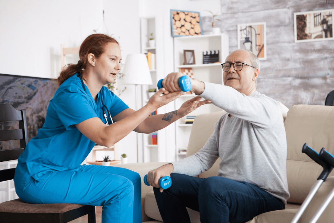 An elderly man holding up dumbell with help from physical therapist