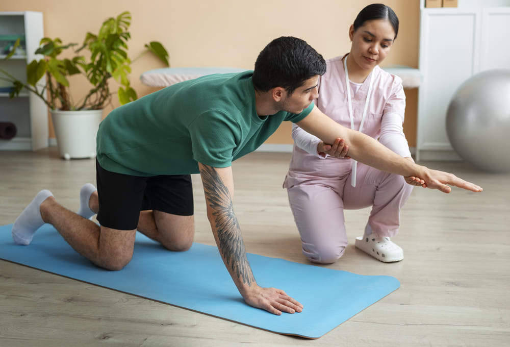patient doing strengthienng exercises on yoga mat with help of therapist