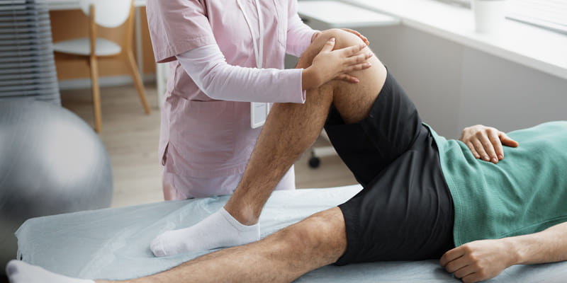 physical therapist stretching man\'s legs
