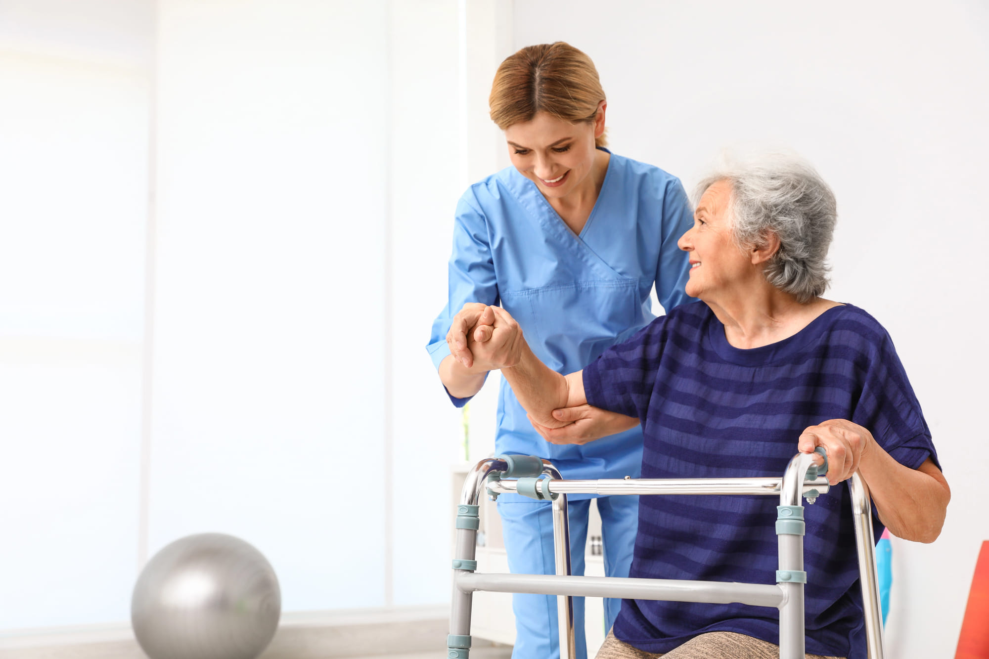 Physical therapist helping elderly woman with walking
