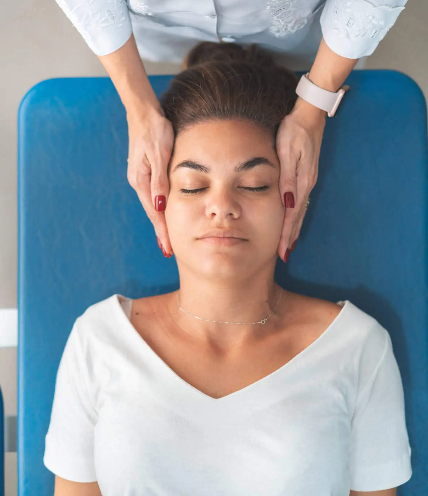 A patient on a massage table getting their head massaged