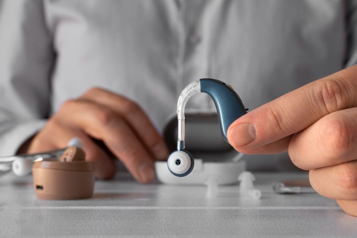 man holding hearing aids on desk