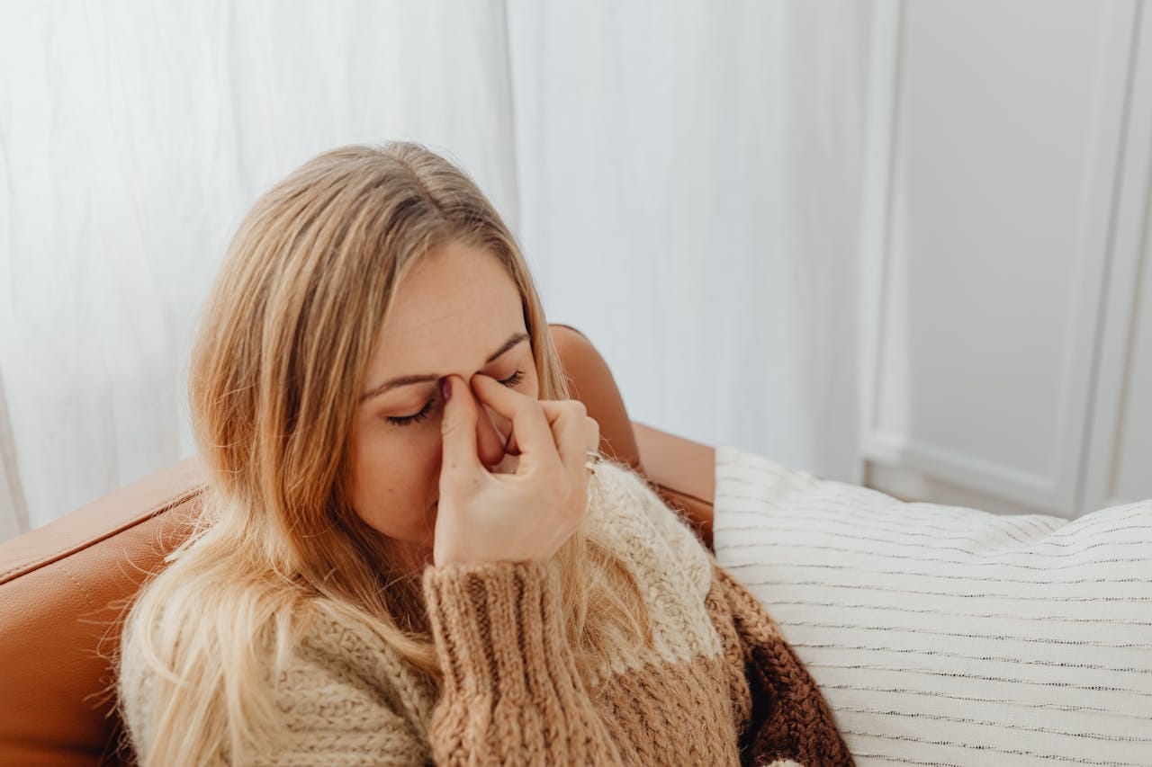 Woman experiencing sinus pressure and nasal congestion symptoms at home