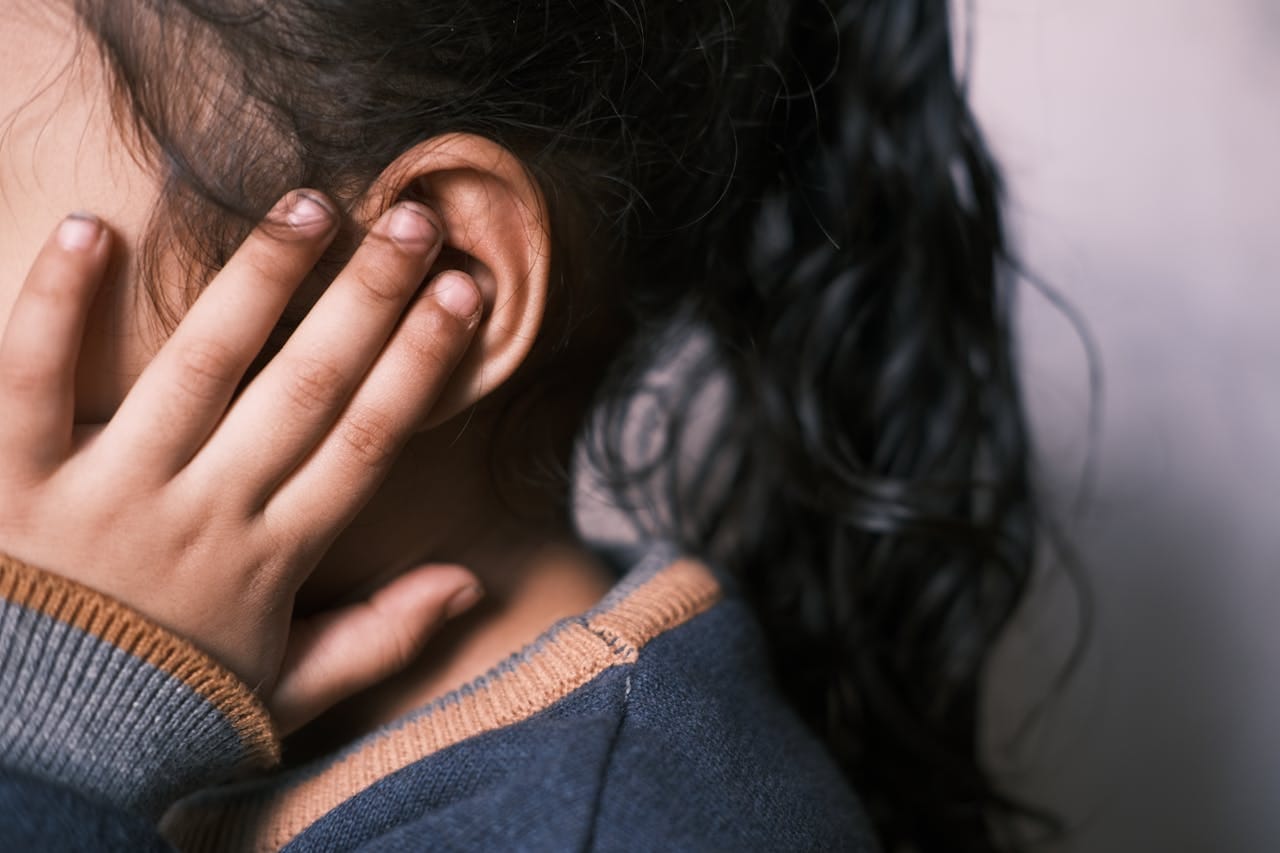 Child covering ear due to ear pain or hearing discomfort before ENT evaluation