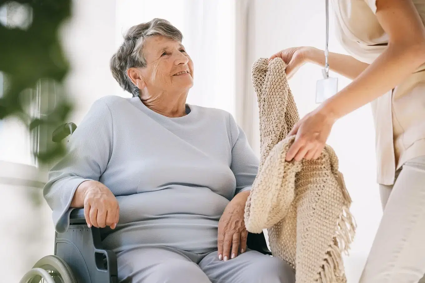 Caregiver giving blanket to elderly woman