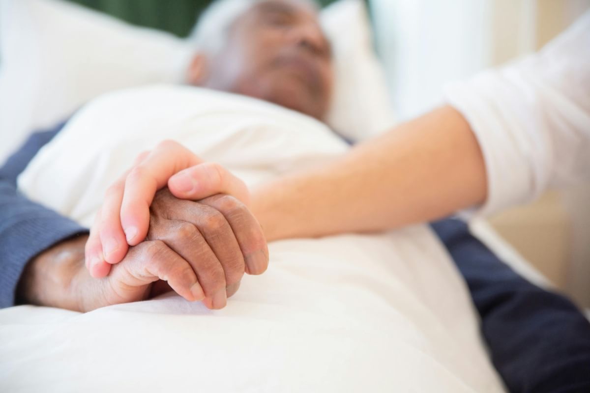 Older man getting his hand held by nurse