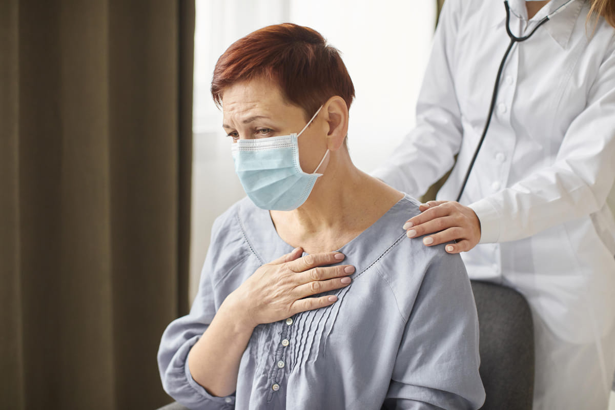 woman holding a hand over her heart as a doctor places hand on her shoulder