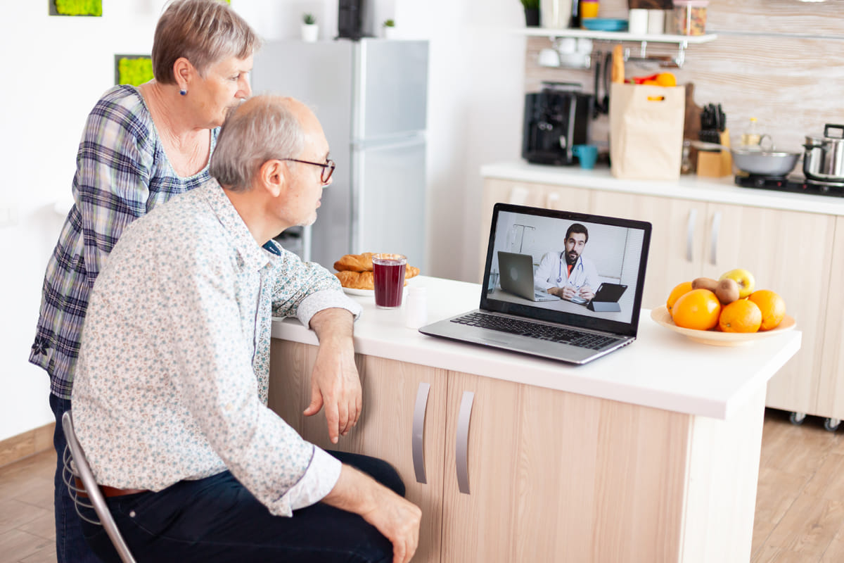 elderly couple talking to doctor on zoom on laptop
