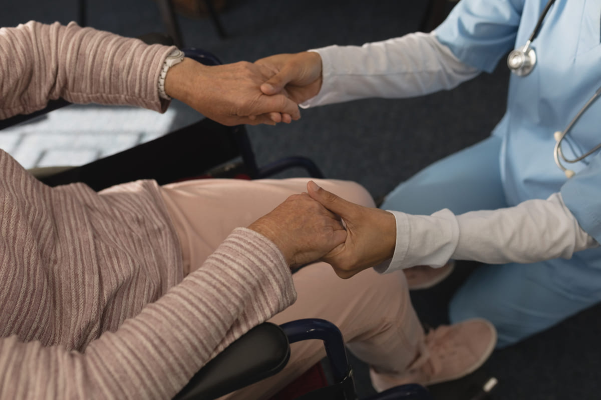 Hospice care doctor holding elderly woman\'s hands