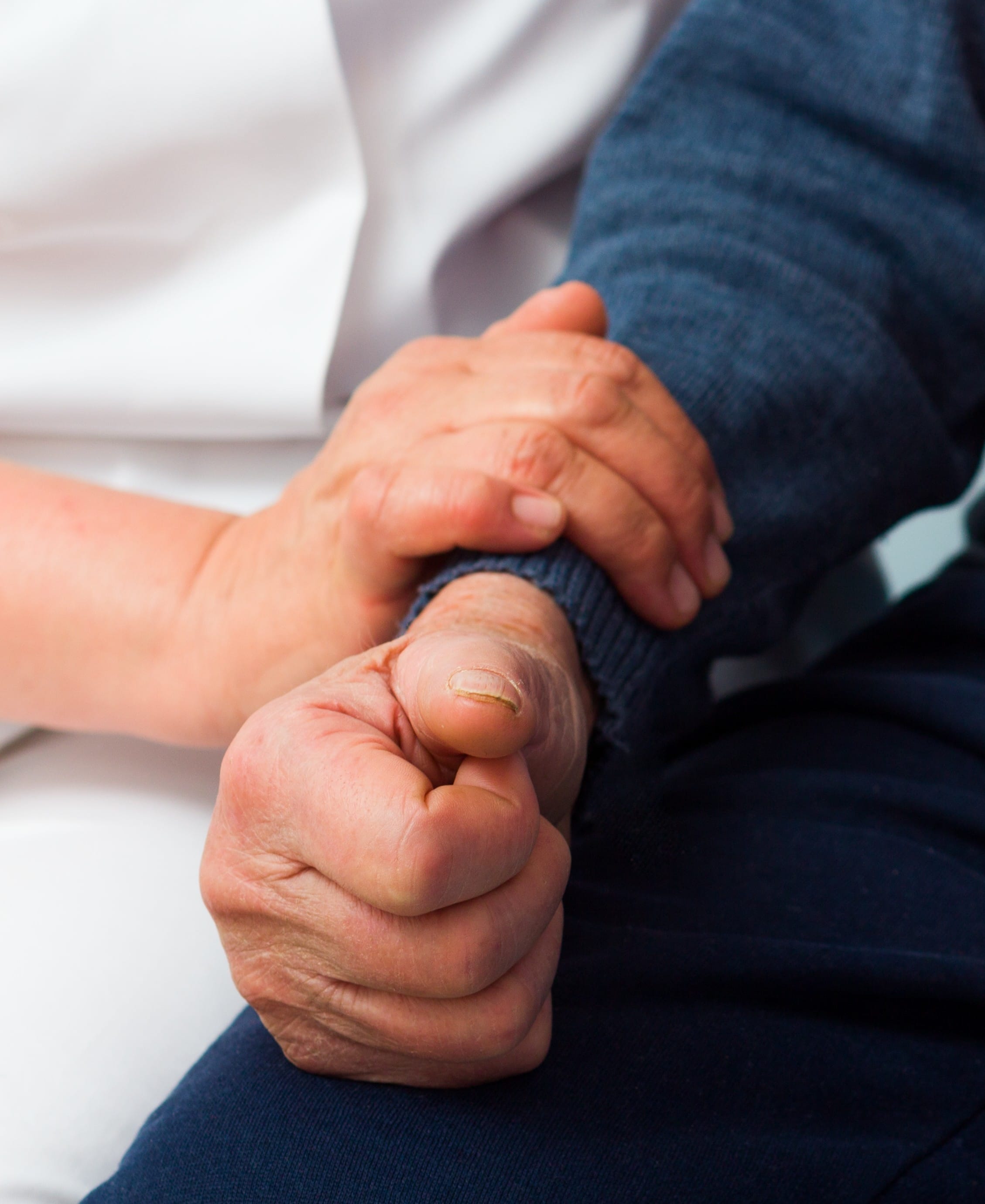 Hospice care worker gently holding patient\'s arm with compassion