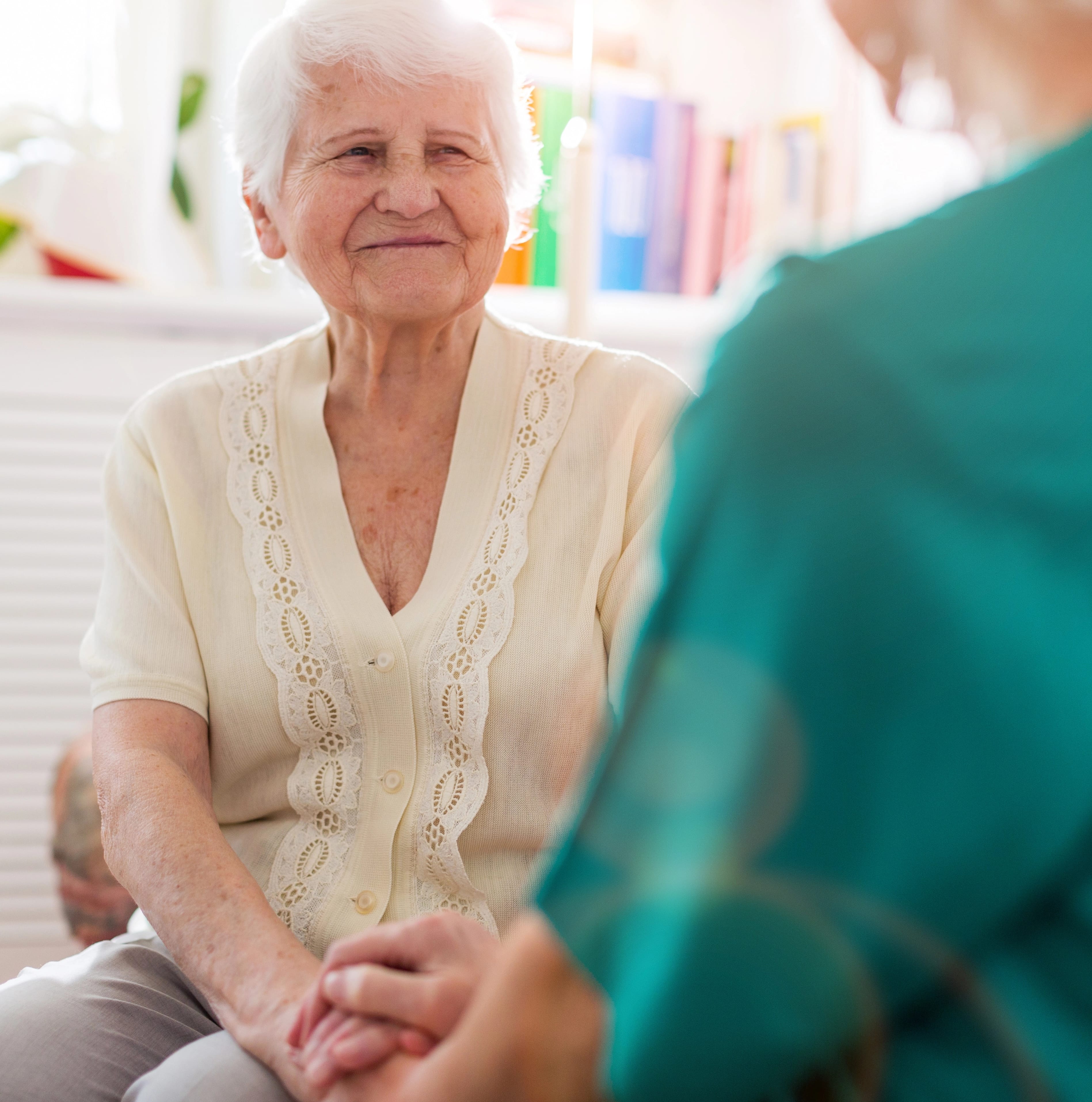 elderly woman in v-neck blouse seated across from doctor