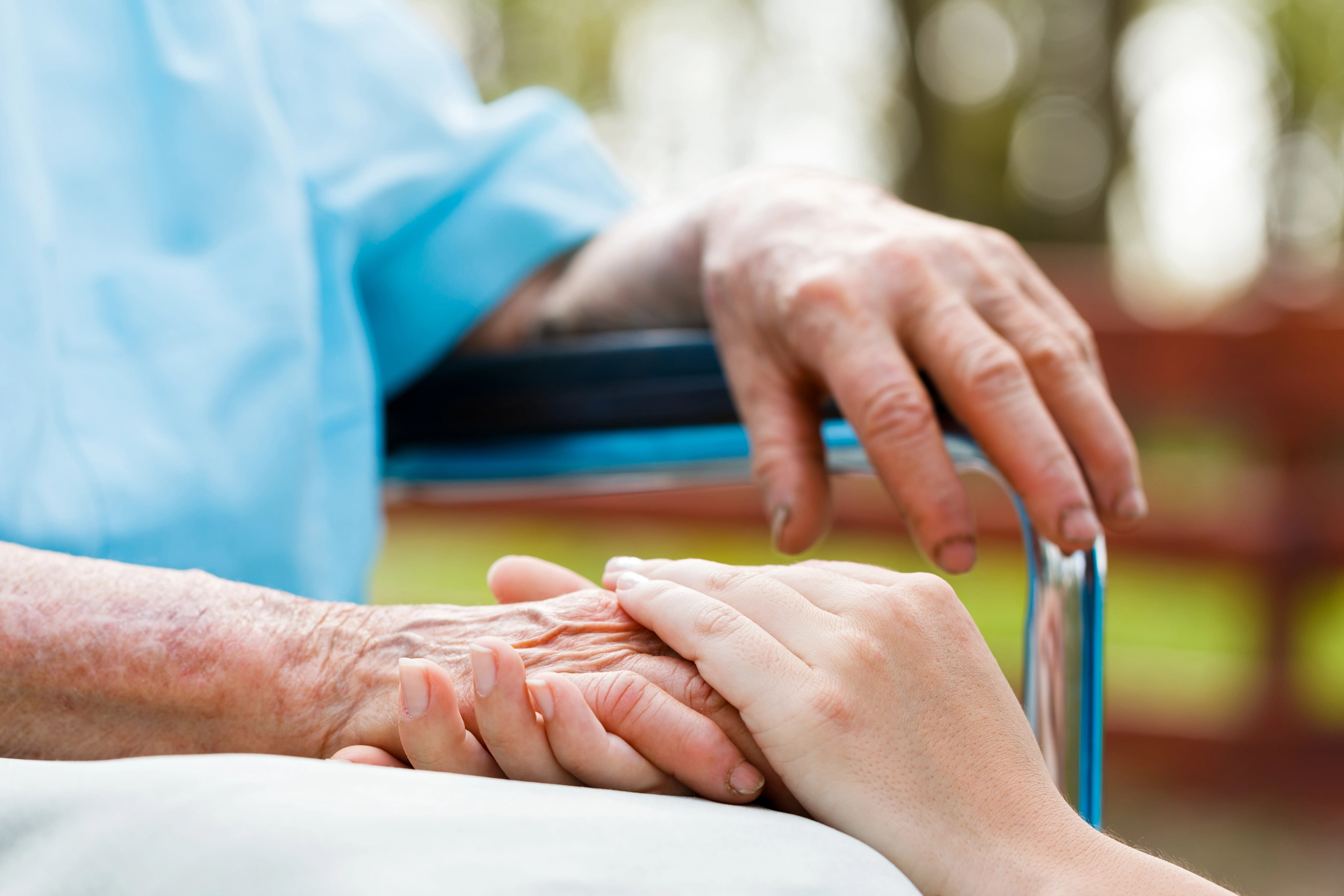 hospice care worker placing hand over the patient\'s hand