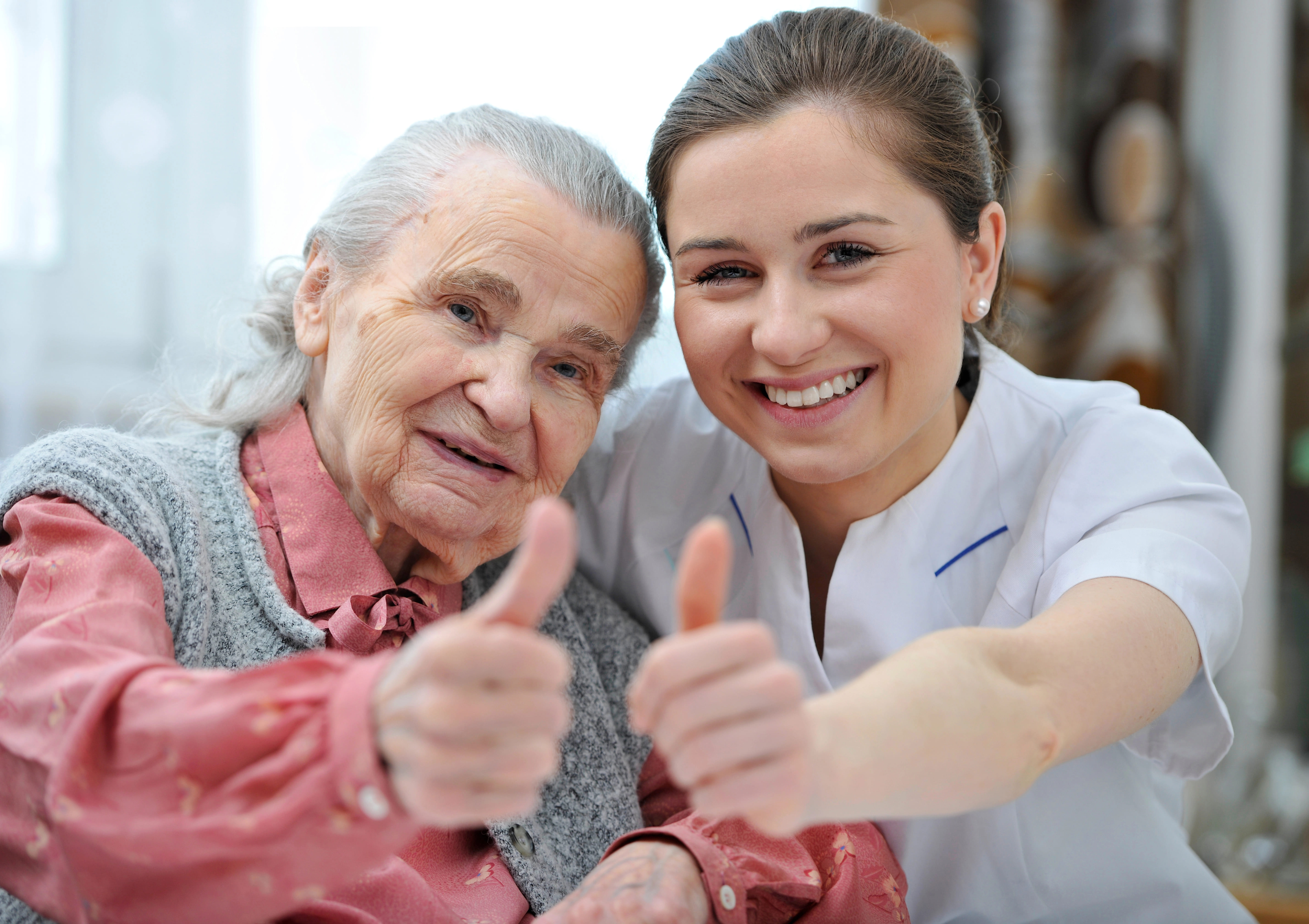 Elderly patient giving a thumbs-up with their care worker