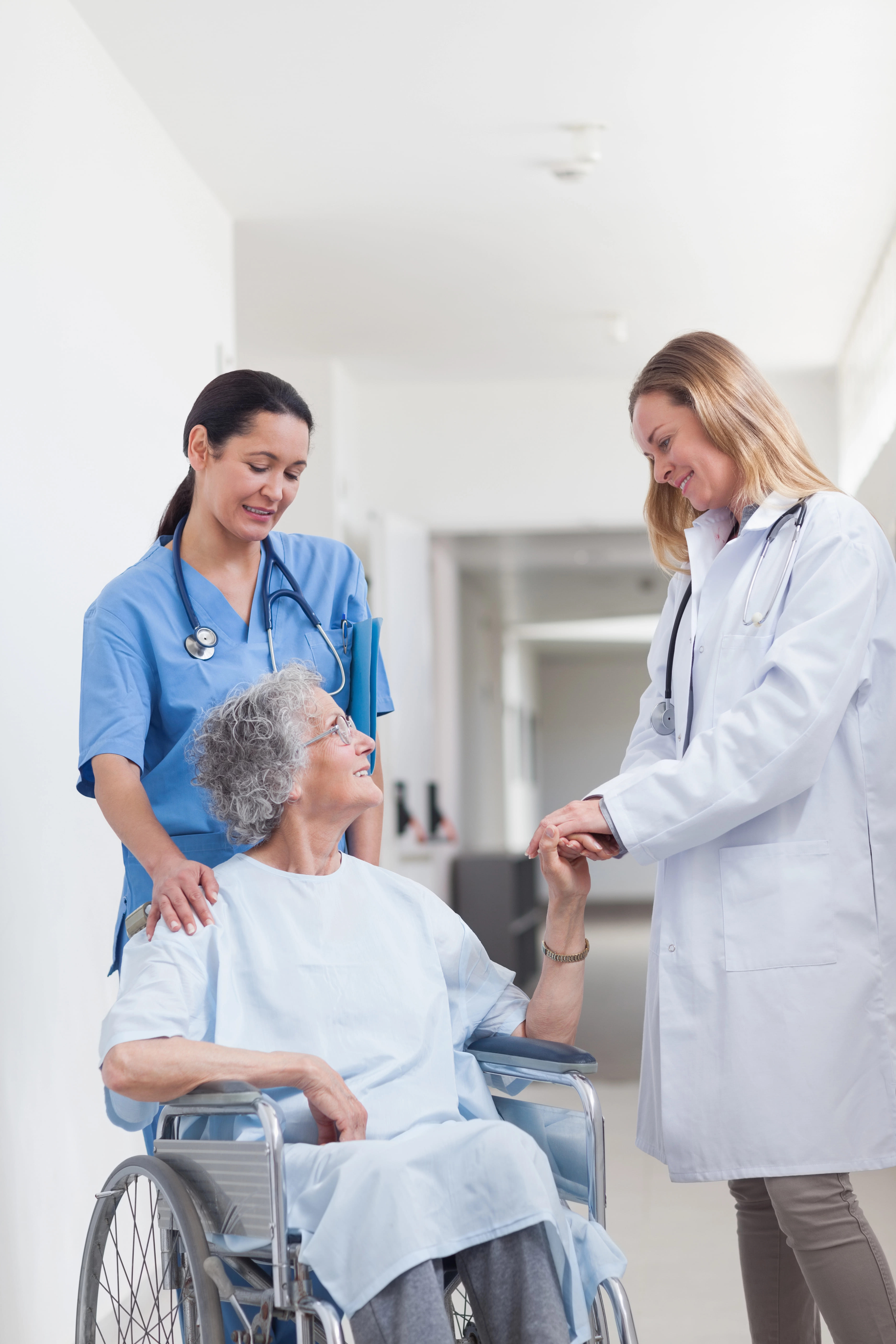 Elederly woman with glasses holding hands with a doctor