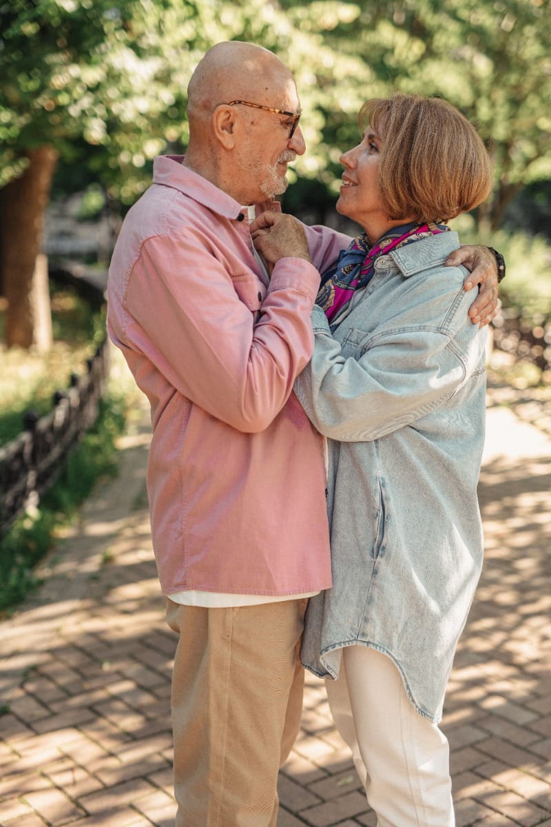 Married couple standing on a pathway as they embrace in the park
