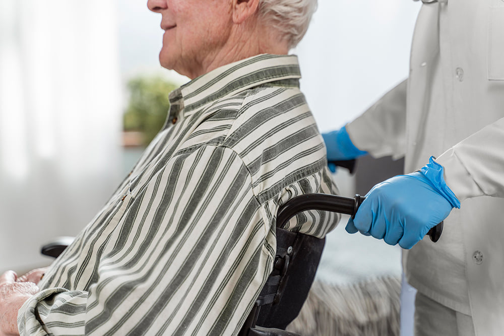 elderly man in white and green stripe collar shirt as he sits waiting for an appointment