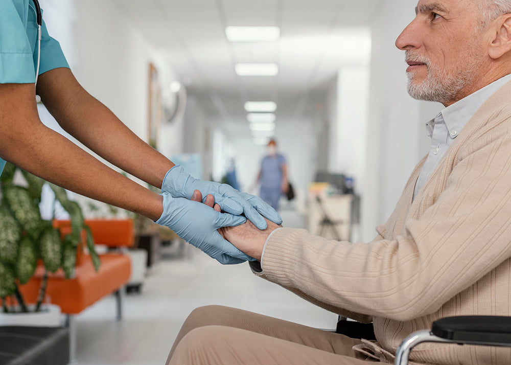 patient sitting in a hospital holding hands with a doctor with latex gloves