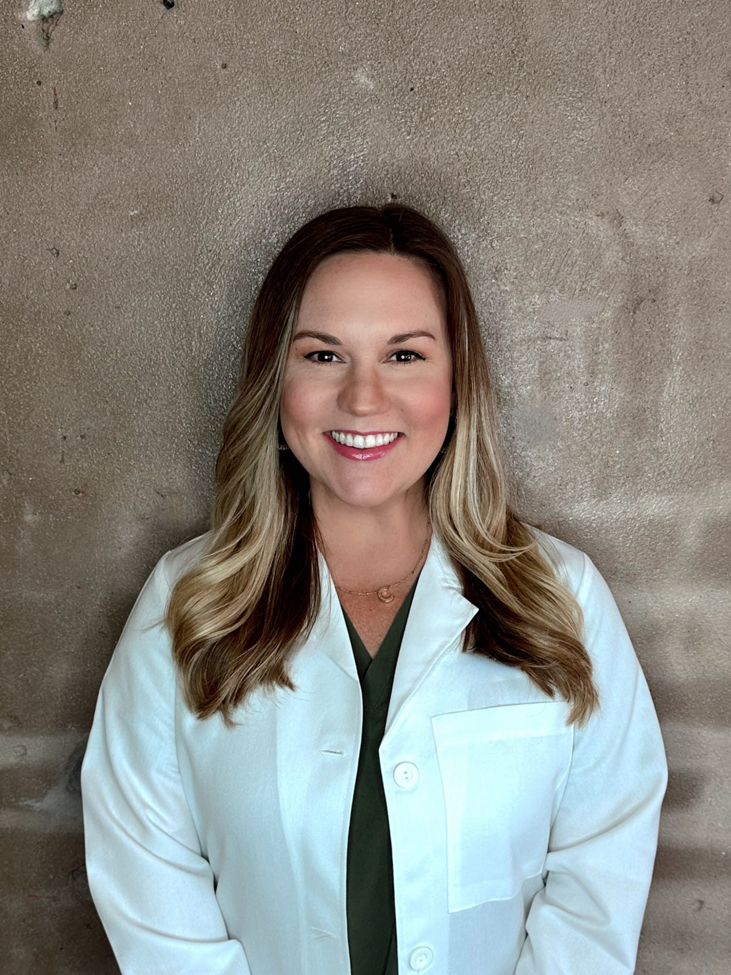 Female dermatologist smiling in a white medical coat.