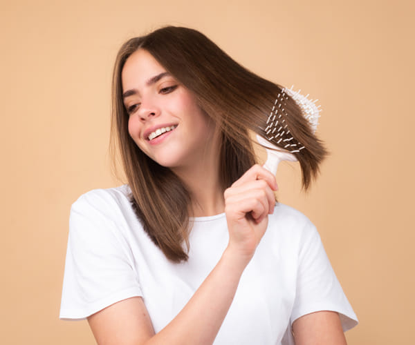 young woman smiling as she runs hairbrush through short hair
