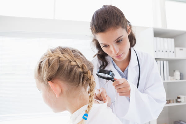 Pediatric dermatologist using microscope to view the skin on child\'s neck