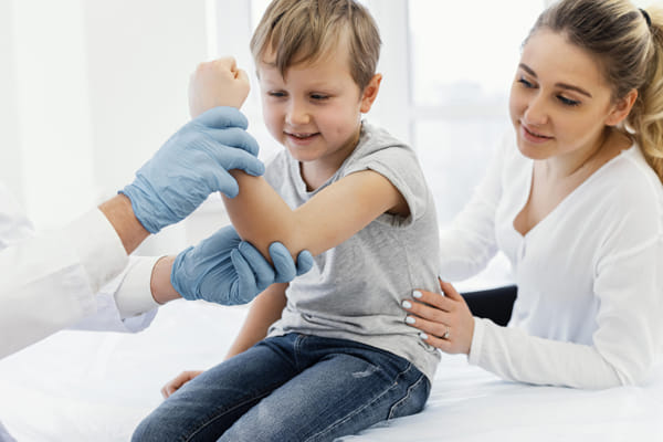 A pediatric dermatologist looking over child\'s arm in dermatology office