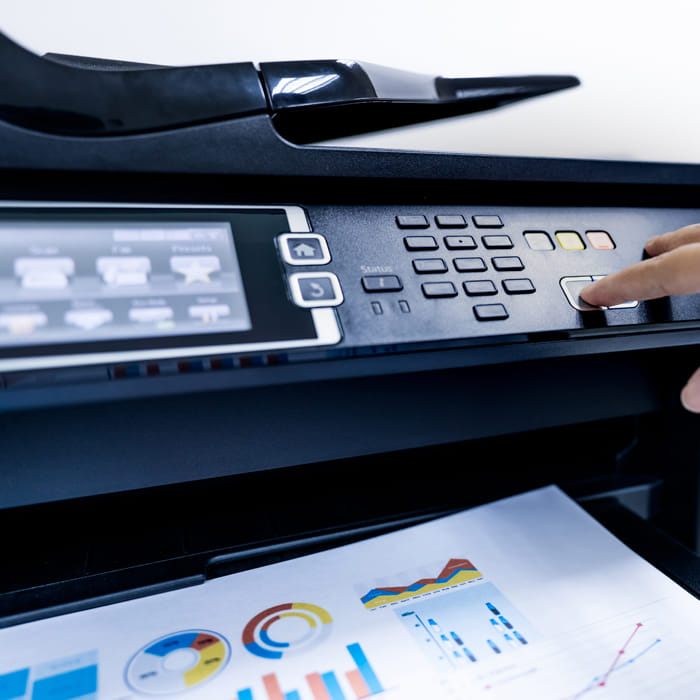 Employee reviewing printed business report from multifunction printer