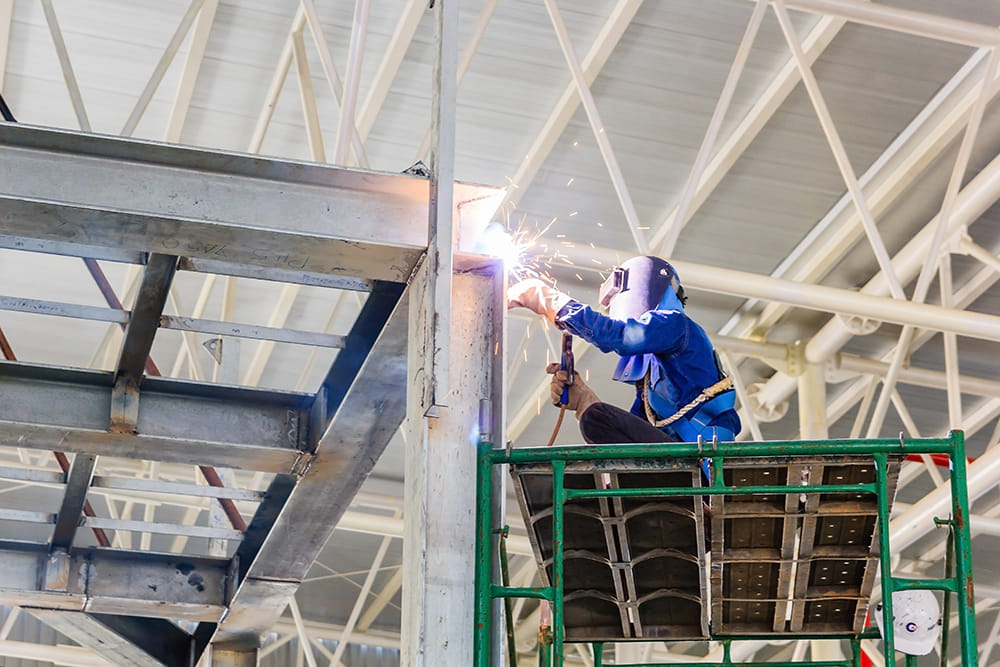 Welder using torch on steel frame in a warehouse
