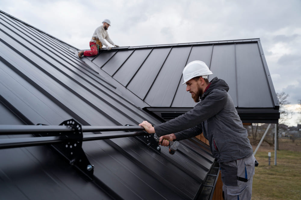 Roofing contractors installing standing seam metal roof panels on residential structure