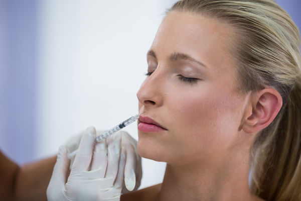 cosmetic surgeon injecting fillers above woman\'s lips
