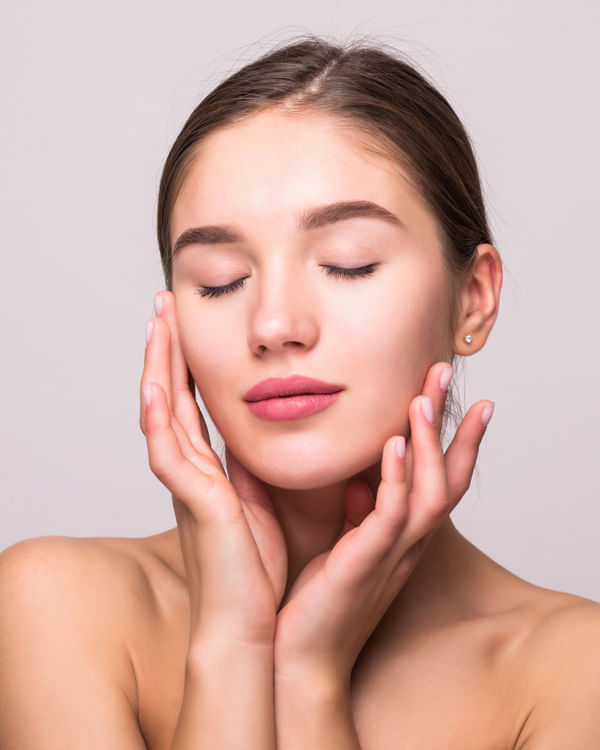 young woman touching her face with manicured fingers