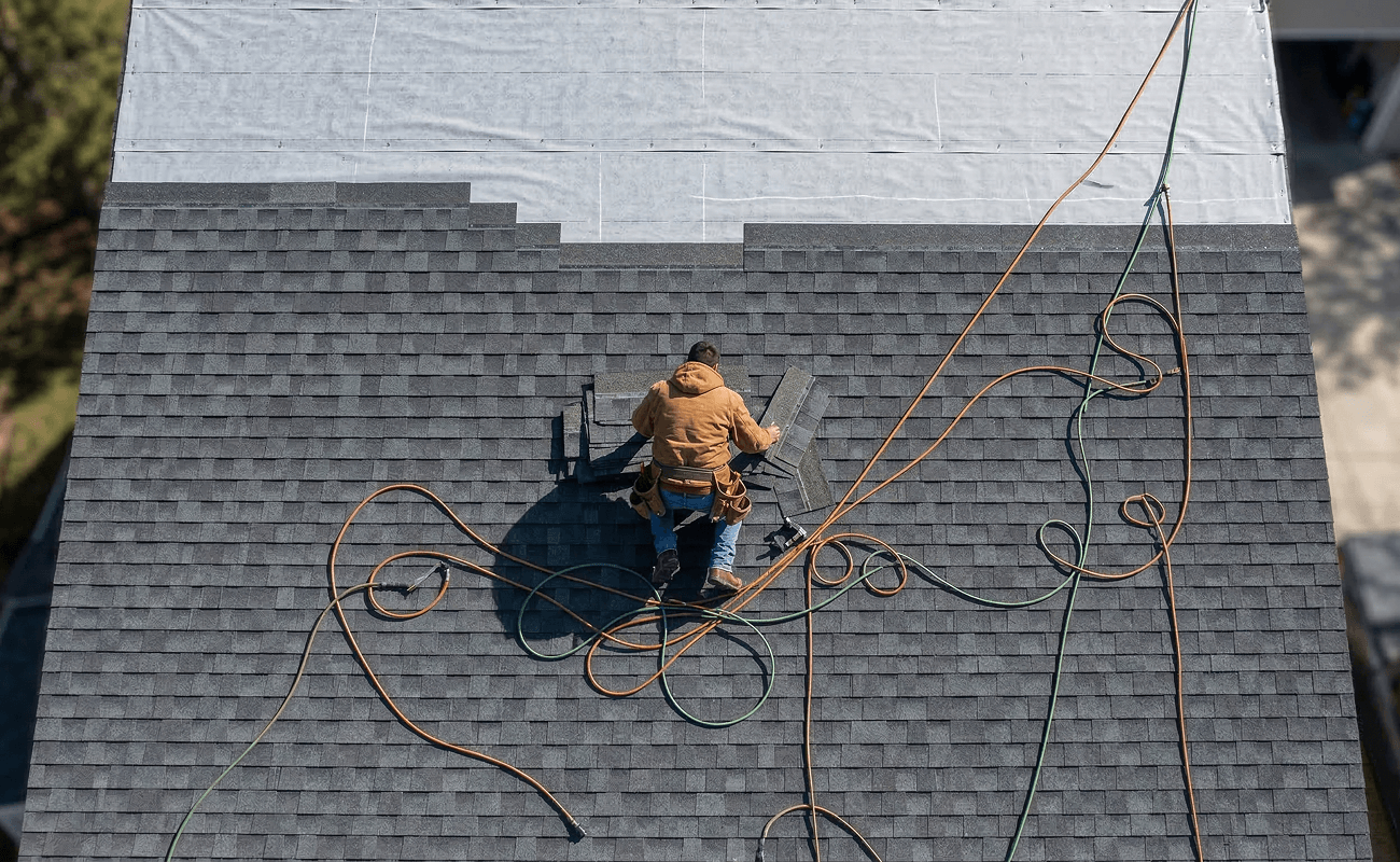 Roofer repairing asphalt shingles on residential roof